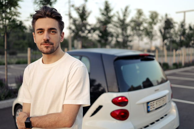 A man in a white shirt next to a white car