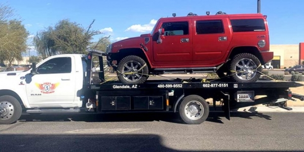 A red vehicle being towed by Fast 5 Towing